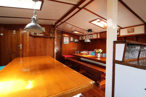 Wooden dining table beside the stairs in the saloon of the Anna Trijntje