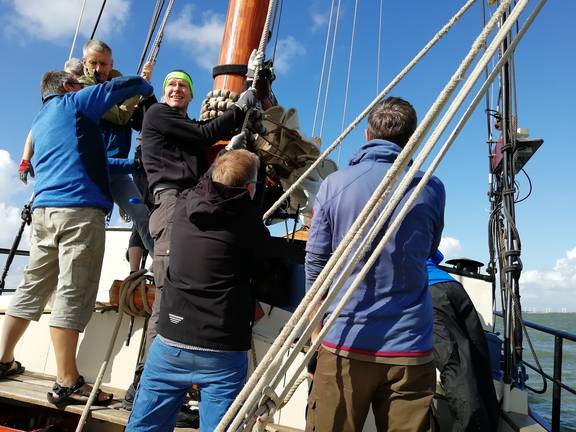 Guests hoisting a sail together on the Avontuur