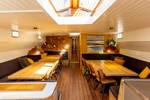 Saloon with wooden dining tables and benches on the Avontuur