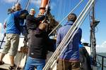 Guests hoisting a sail together on the Avontuur