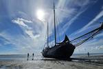 The tjalk Aagtje resting on the tidal flats with people beside the ship
