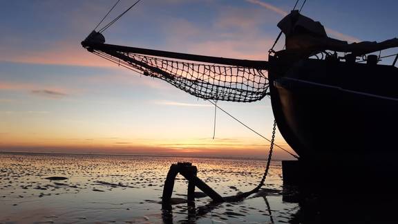 Bow of the tjalk Aagtje at sunset on the Wadden Sea