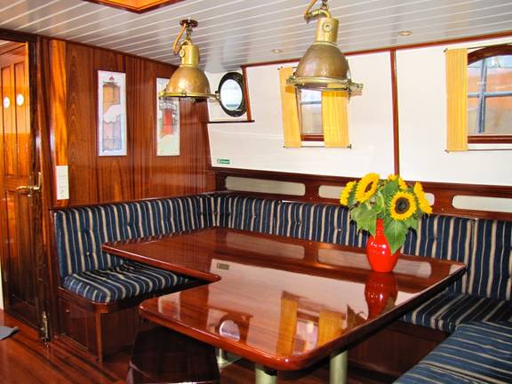 Saloon with a wooden table and benches on the tjalk Aagtje