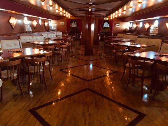 Saloon of the Abel Tasman with wooden tables and ambient lighting
