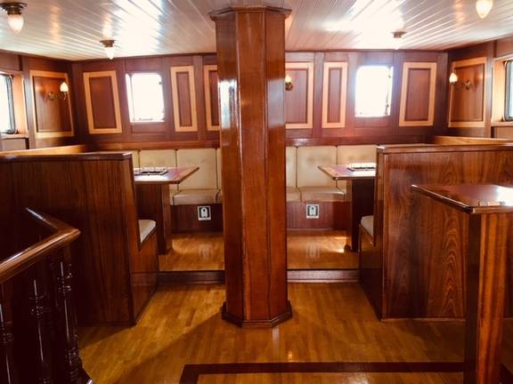 Wooden benches and tables in the saloon of the Abel Tasman