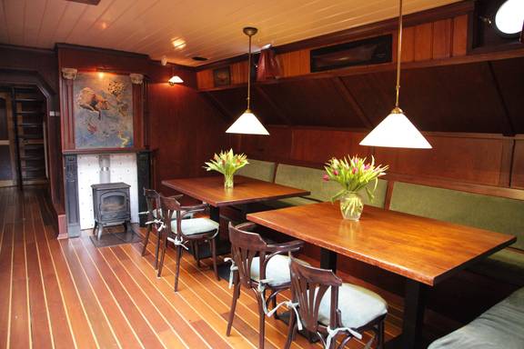 Saloon of the Aldebaran with wooden dining tables and red benches