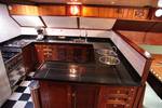 Wooden galley of the Aldebaran with a cooker and black-and-white tiled floor