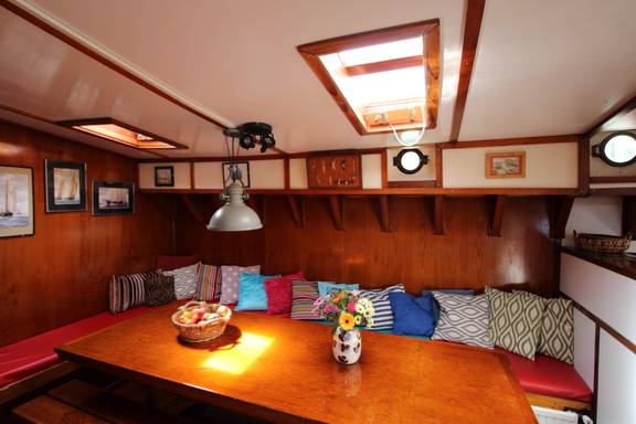 Wooden dining table and bench seating in the saloon of the Anna Trijntje