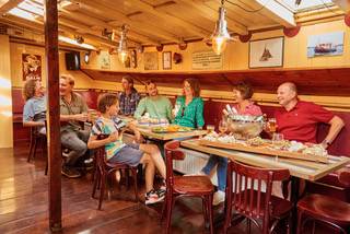 Guests at a table in the wood-panelled saloon of the clipper Anna