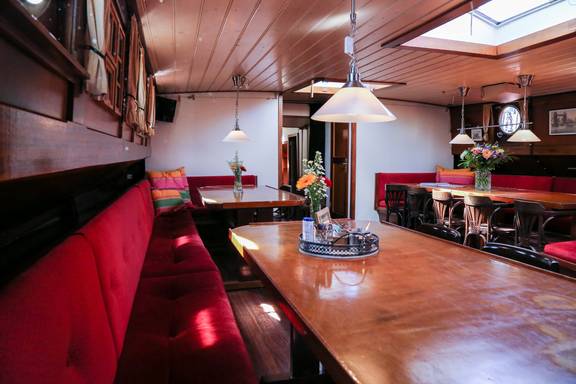 Saloon of the Avondrood with wooden dining tables and red benches