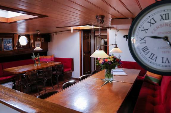 Dining tables and a wall clock in the saloon of the Avondrood
