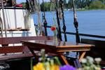 Wooden table on the deck of the Avondrood with a view of the water