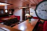 Dining tables and a wall clock in the saloon of the Avondrood