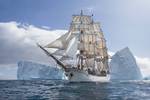 Barque Europa sailing past a large iceberg