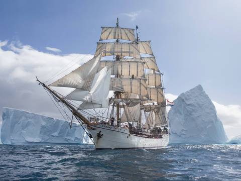 Barque Europa sailing past a large iceberg