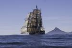 Barque Europa sailing along a mountainous coast