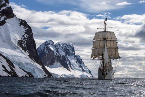 Barque Europa under sail beside snow-covered mountains