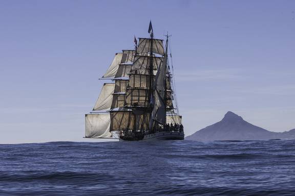 Barque Europa sailing along a mountainous coast