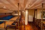 Wood-panelled saloon of the Summertime with dining tables and benches