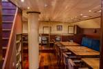 Wood-panelled saloon of the Summertime with dining tables and benches
