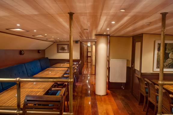 Wood-panelled saloon of the Summertime with dining tables and benches