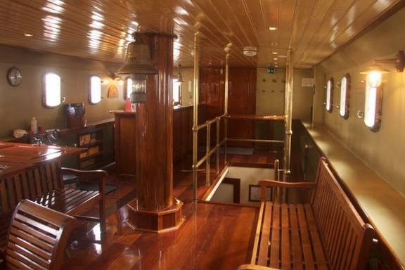Wood-panelled saloon of the Summertime with dining tables and benches