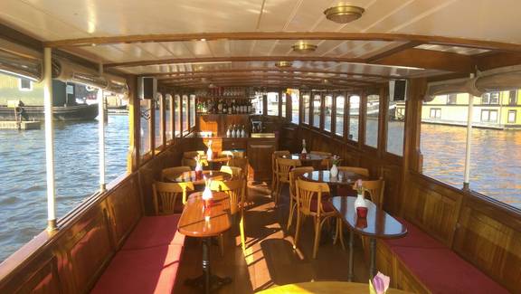 Wooden tables and chairs in the saloon of the Belle van Zuylen