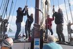 Guests hoisting a sail together on the deck of the Boekanier