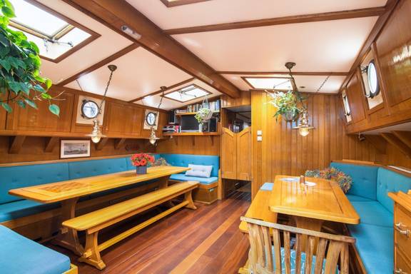 Wooden dining tables and blue bench seating in the saloon of the Bonnefooi