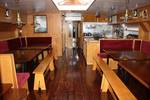 Saloon of the Broedertrouw with wooden dining tables and red benches