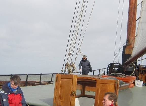 Guests on the deck of the Broedertrouw beneath a cloudy sky