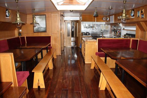 Saloon of the Broedertrouw with wooden dining tables and red benches
