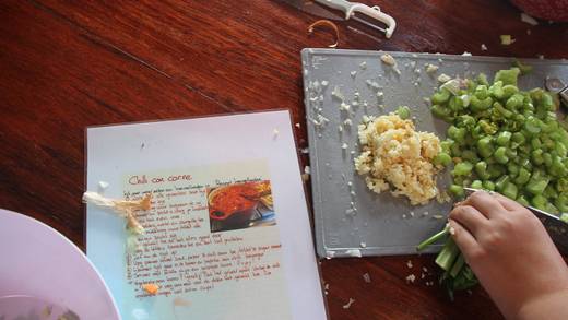 Chopping vegetables beside a recipe for chilli con carne