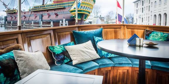 Seating area with turquoise cushions on the aft deck of the Dame van Amstel