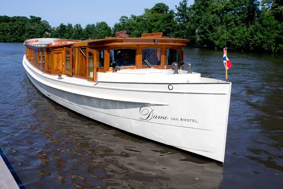 Saloon boat Dame van Amstel with a wooden cabin on the water
