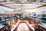 Bright saloon of the Dame van Amstel with wooden tables and turquoise benches