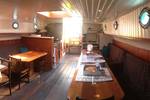 Seating area with a dining table beneath the wooden ceiling of the Dankbaarheid