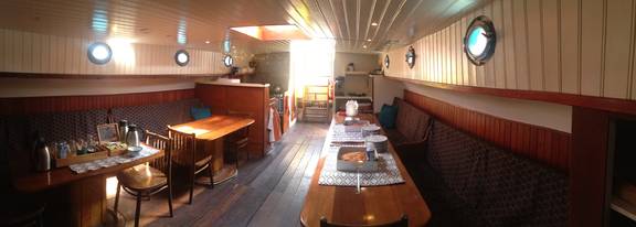 Seating area with a dining table beneath the wooden ceiling of the Dankbaarheid