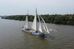 De Hester under sail with a dinghy alongside