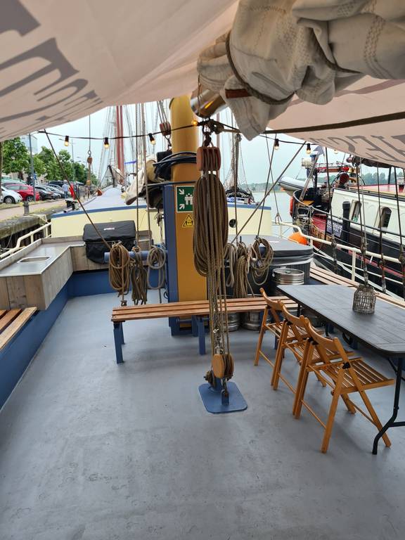 Deck seating area of De Hester with benches and a table beneath a sun canopy