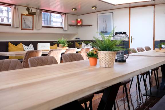 Long dining tables with plants in the saloon of De Hester