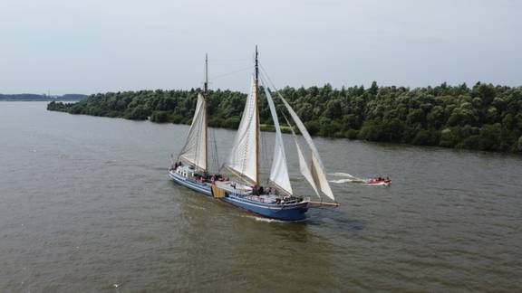 De Hester under sail with a dinghy alongside
