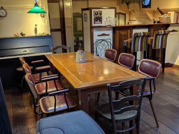 Saloon of the Engelburg with a dining table, piano and bar