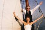 Wedding couple posing with outstretched arms beside the sails of the Frisius van Adel