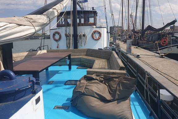 Wooden benches, table and beanbag on the deck of the Grietje