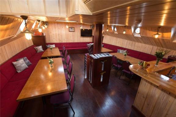 Saloon of the Grietje with wooden dining tables and red benches