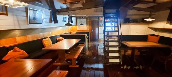 Saloon of the Johanna Engelina with dining tables and stairs to the deck