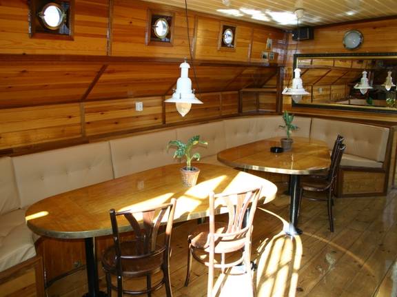 Seating area with a wooden dining table in the saloon of the Korevaer