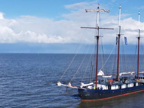 Leafde fan Fryslân with sails lowered on open water