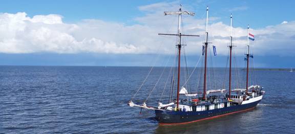 Leafde fan Fryslân with sails lowered on open water